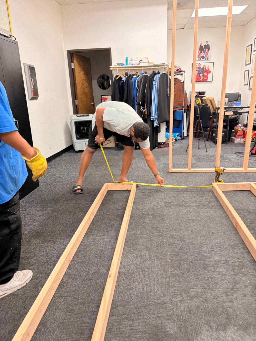 Xavier measuring new wall framing laid out on an office floor