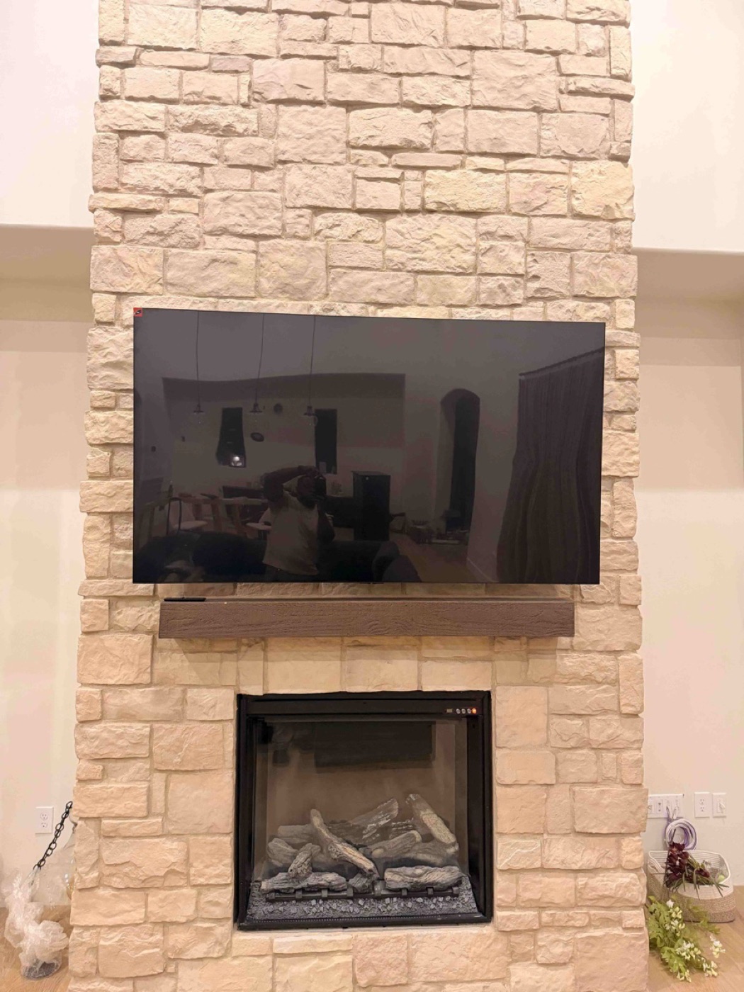 A large TV mounted on a stone fireplace above the mantel